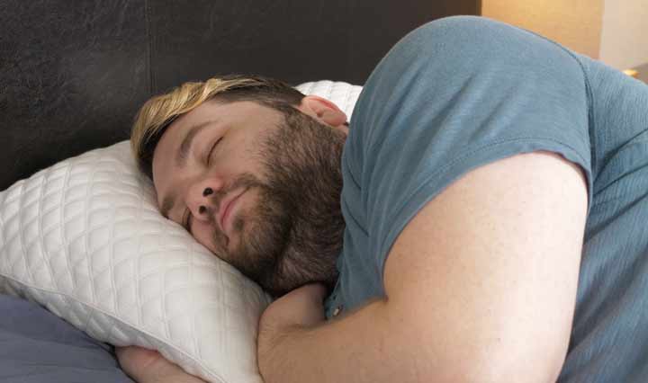 A man sleeps on his side on a Nolah Squishy pillow